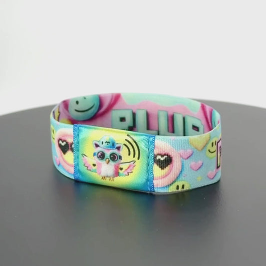 8-second rotating video of the wristband’s back, showcasing bold 3D-style “PLUR” lettering in mint green outlined in black over a pink and cyan gradient, framed by pixel-art smiles and hearts.