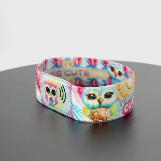 Continue the spin to reveal the opposite side of the band—show the repeating owl motifs and pastel petals—completing a full 360° wrist rotation.
