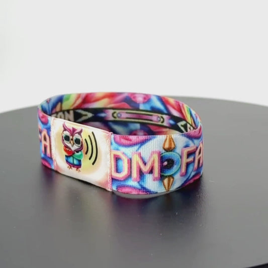 8-second rotating video of the wristband’s back, showcasing bold ‘EDM FAN’ text on a black banner over a kaleidoscopic swirl of rainbow colors and starburst motifs.